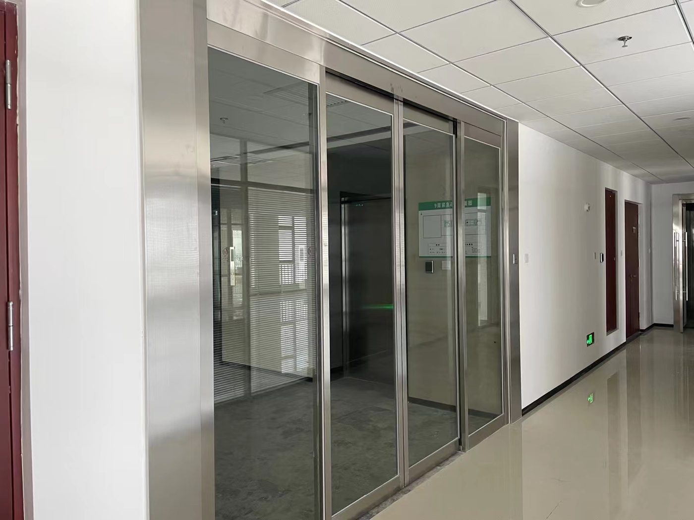 玻璃隔断门：办公楼走廊的玻璃隔断与门体衔接，地面为地砖