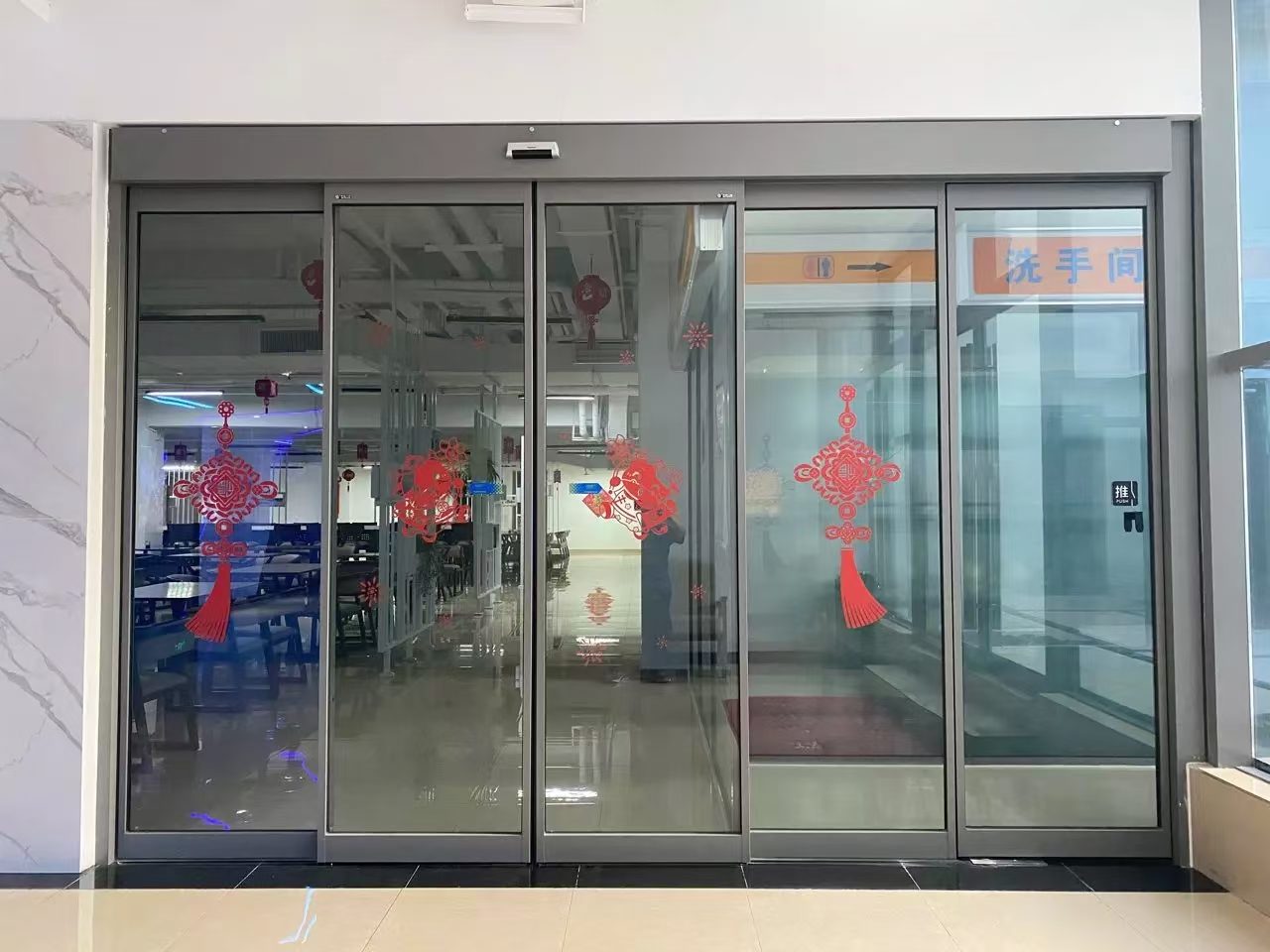四扇玻璃自动门:商厦内四扇并列的玻璃自动门,门洞较宽,上部为吊顶