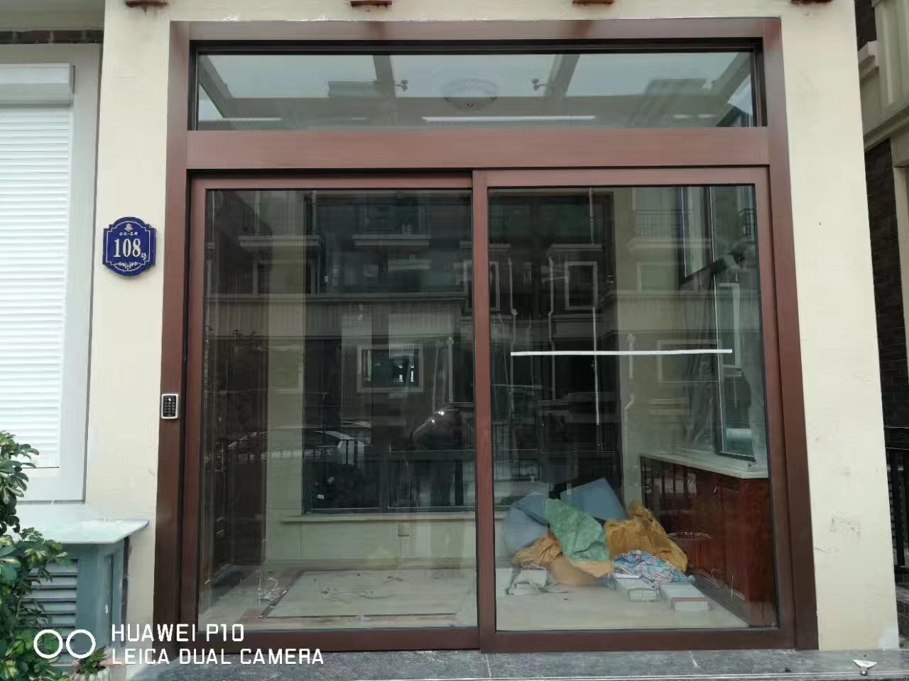 商铺自动门改造：商铺翻新现场，旧门已拆、门洞待修补，周边为饰面与堆放物